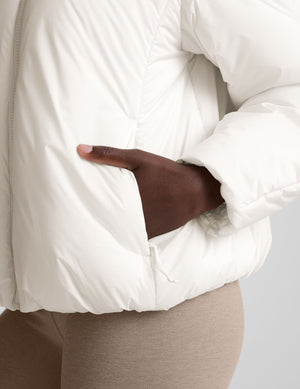 model wearing a white puffer jacket against a plain background. 