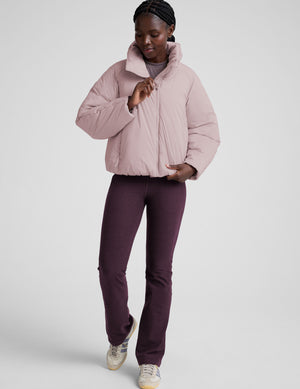 model wearing a light pink puffer jacket on a light background. 