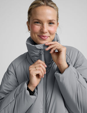 model wearing a gray puffer jacket on a light gray background. 