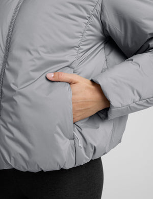 model wearing a gray puffer jacket on a light gray background. 