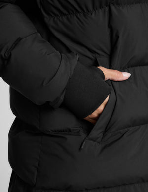 Person wearing a black puffer coat on a light gray background. 