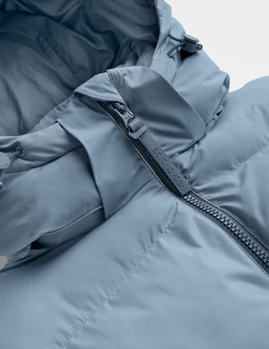 Close-up of a blue puffer jacket with a zipper on a light gray background. 