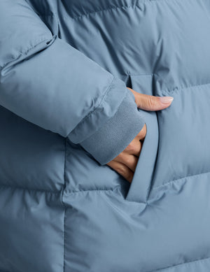 Woman wearing a blue puffer coat on a light gray background