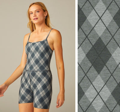 model is wearing a grey argyle printed short jumpsuit. 