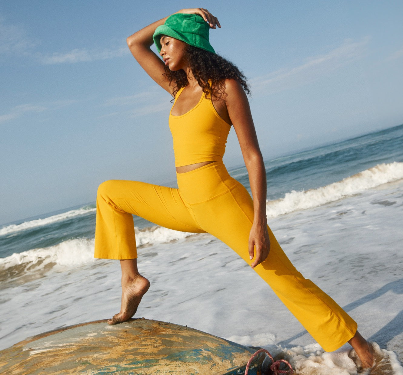 model is wearing a yellow halter cropped tank and yellow cropped flare pants. 