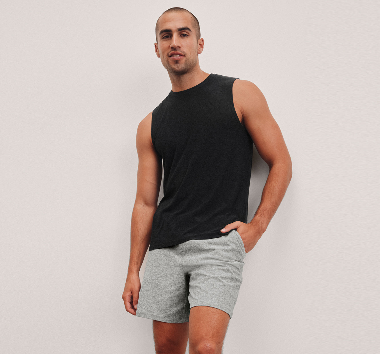 model is wearing a black mens tank and grey mens shorts. 