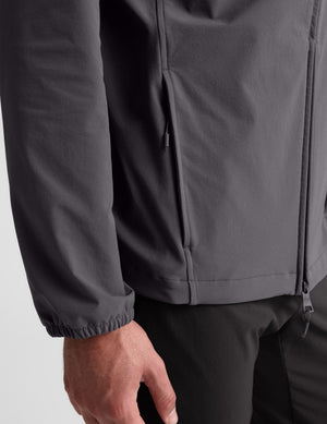 Man wearing a gray hooded jacket on a light gray background. 