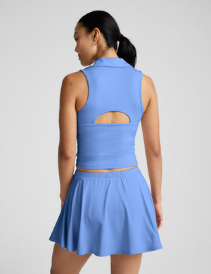 Woman in a blue polo tank and mini skirt with white piping down the sides against a plain background. 