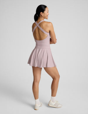 Woman wearing a light pink dress with thin straps on a plain background. 