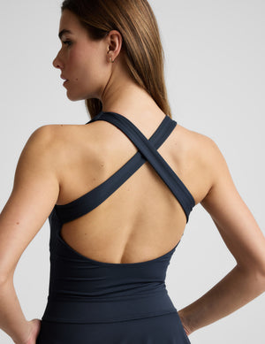 Woman wearing a navy blue dress against a plain background. 