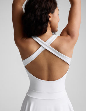 Woman wearing a white dress against a plain background. 