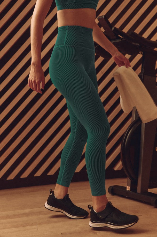 model is wearing green high-waisted midi ribbed leggings. 