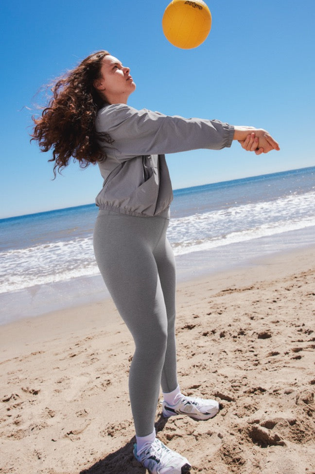 model is wearing a gray stretch woven jacket and gray high-waisted midi leggings. 