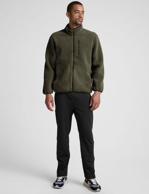 model wearing a men's green fleece zip-up jacket on a light gray background. 