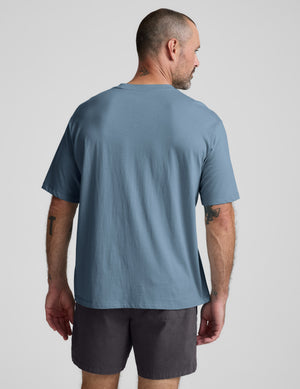 Man wearing a blue cotton t-shirt and gray shorts against a plain background. 