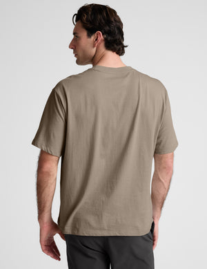 Man wearing a plain brown t-shirt against a light gray background
