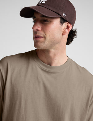 Man wearing a plain brown t-shirt against a light gray background