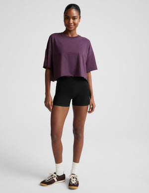 Woman wearing a purple top and black shorts on a white background
