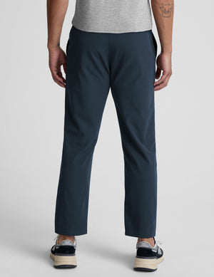 Person wearing navy pants on a plain background. 