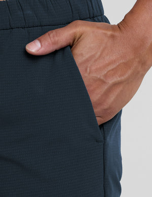 Close-up of navy Dynamic Men's Straight Leg Pant showing a hand in the side pocket and the elastic waistband's texture.