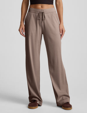Brown wide-leg corduroy pants worn by a person on a light gray background. 