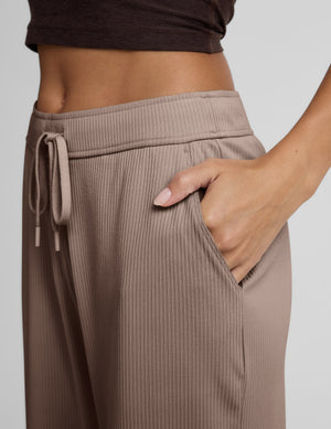 Brown wide-leg corduroy pants worn by a person on a light gray background. 