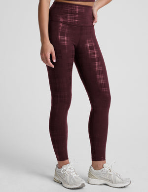 model wearing a plaid foil high-waisted midi leggings on a light gray background. 