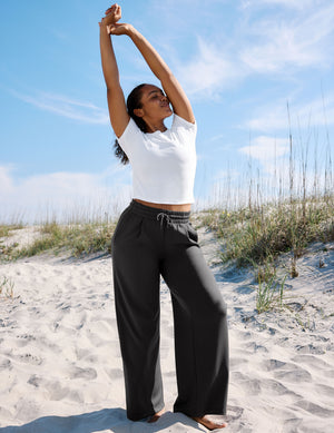 Woman wearing a white t-shirt and charcoal wide leg pants. 