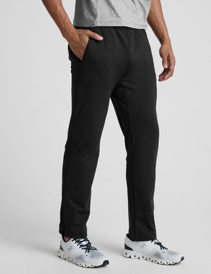 person wearing black pants and white sneakers on a light gray background