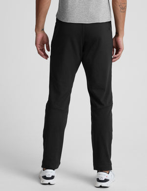 person wearing black pants and white sneakers on a light gray background