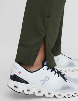 white athletic shoes worn with green pants on a light gray background. 