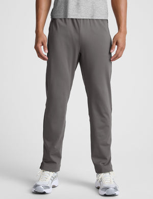 man wearing a gray shirt and gray pants on a white background. 