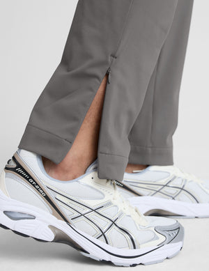 man wearing a gray shirt and gray pants on a white background. 