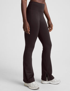 woman wearing a brown sleeveless top and pants on a white background. 
