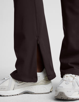 woman wearing a brown sleeveless top and pants on a white background. 
