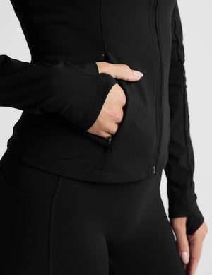 Woman wearing a black jacket on a light gray background. 