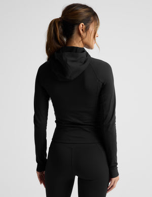 Woman wearing a black jacket on a light gray background. 