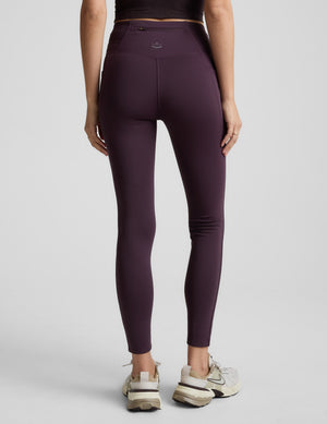 Person wearing purple leggings on a light gray background. 