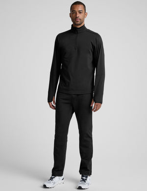 man wearing a black quarter-zip pullover against a plain background. 