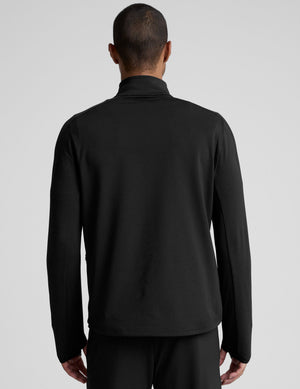 man wearing a black quarter-zip pullover against a plain background. 