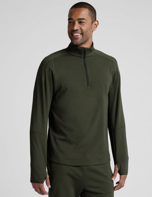 man wearing a green quarter zip pullover against a plain background. 