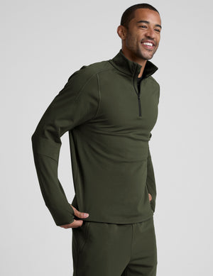 man wearing a green quarter zip pullover against a plain background. 