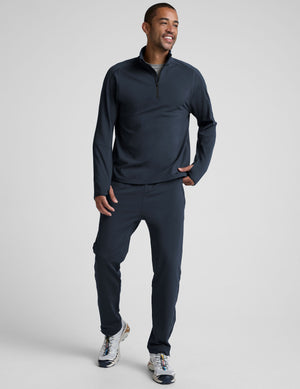 man wearing a dark blue quarter zip pullover against a plain background. 