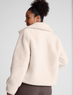 model wearing a light faux fur zip-up jacket against a plain background. 