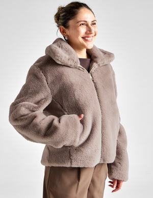 Woman wearing a brown fleece jacket on a white background. 