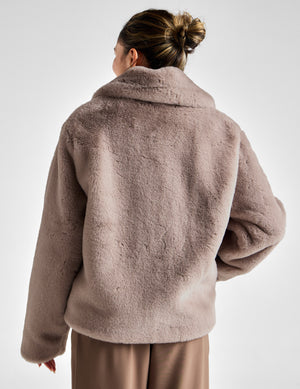 Woman wearing a brown fleece jacket on a white background. 