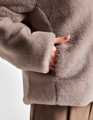 Woman wearing a brown fleece jacket on a white background. 