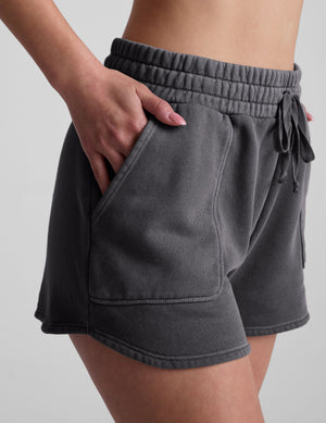 Gray Cali Short with elastic drawstring waistband, patch pockets, and curved dolphin hem on a model.