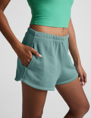 Turquoise Fade Out Mid-Rise Short with a gathered waistband, side pockets, and curved dolphin hem on a model.