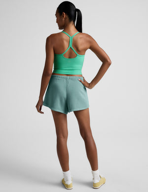 Rear view of model wearing turquoise Fade Out Mid-Rise Short with a curved dolphin hem and gathered elastic waistband.